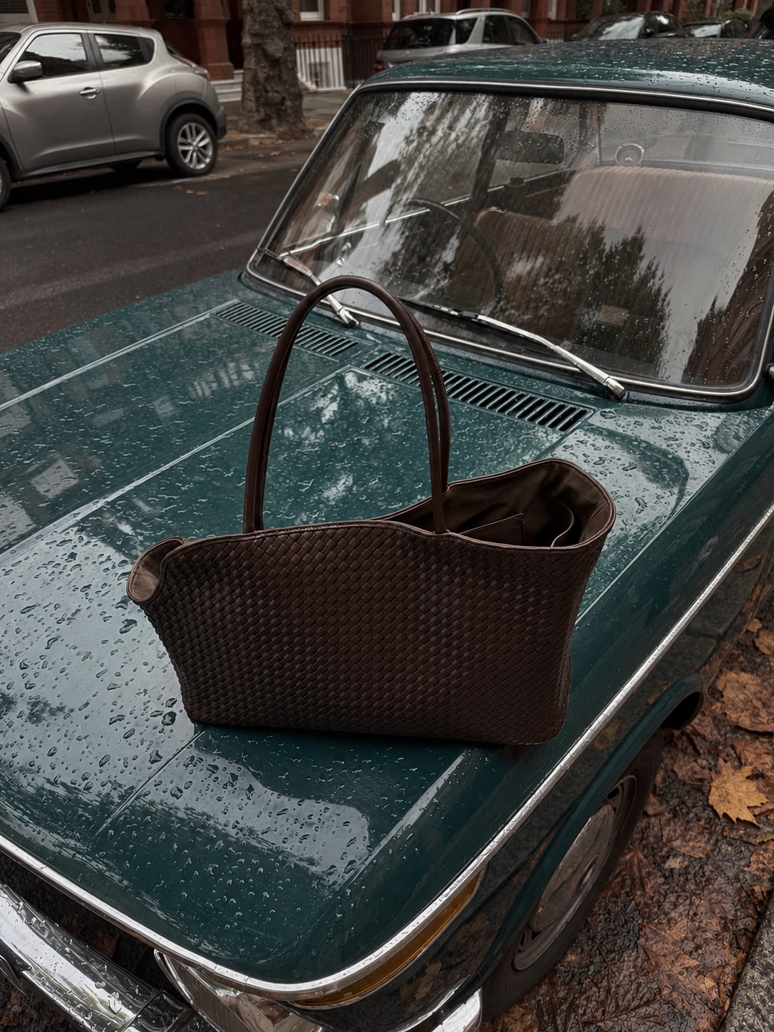 A brown woven CHILLI carrier on a rain-covered vintage green car